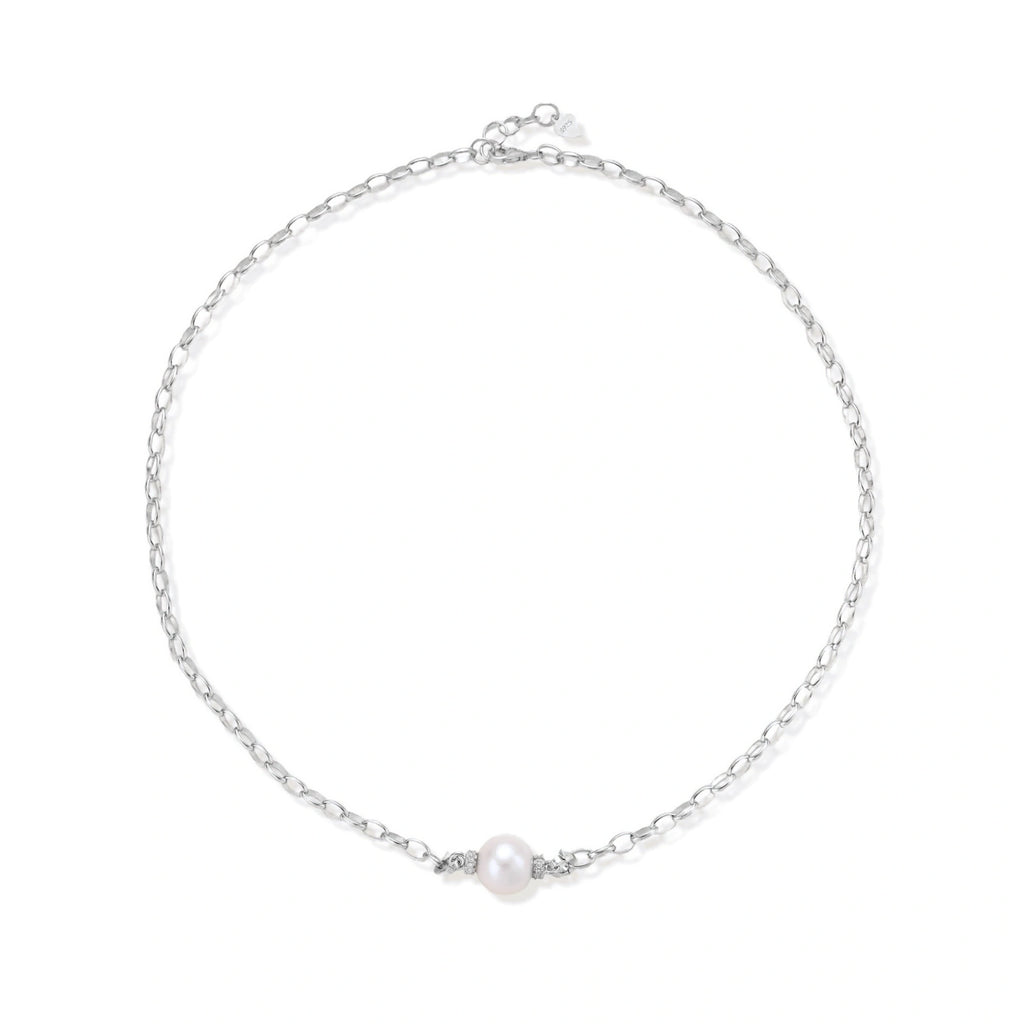 Dainty rhodium-plated silver chain necklace with centered 10mm freshwater pearl and crystal accents on cream background