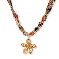 Vibrant patterned fabric necklace with gold-toned flower pendant featuring rhinestone center on white background