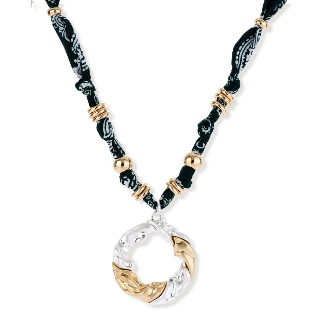 Adjustable necklace with black paisley fabric cord, gold metal spacers, and clear twisted pendant on cream background