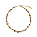 Beaded necklace on a wooden tray with a card underneath