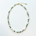 Beaded necklace with green and white stones on a jewelry display box.