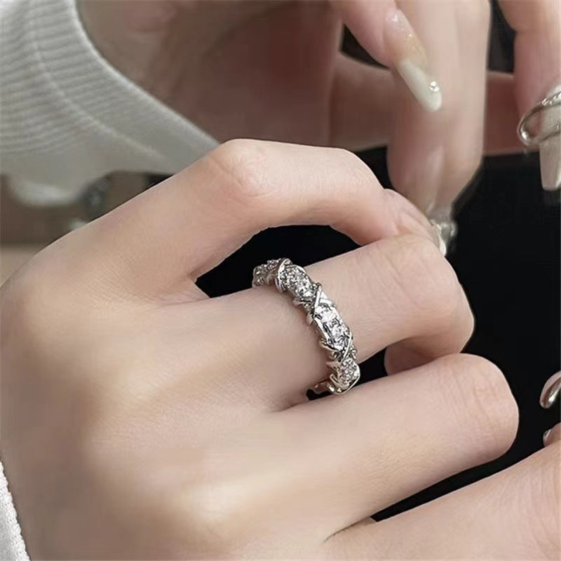 Close-up of a hand wearing a silver ring with gemstones.