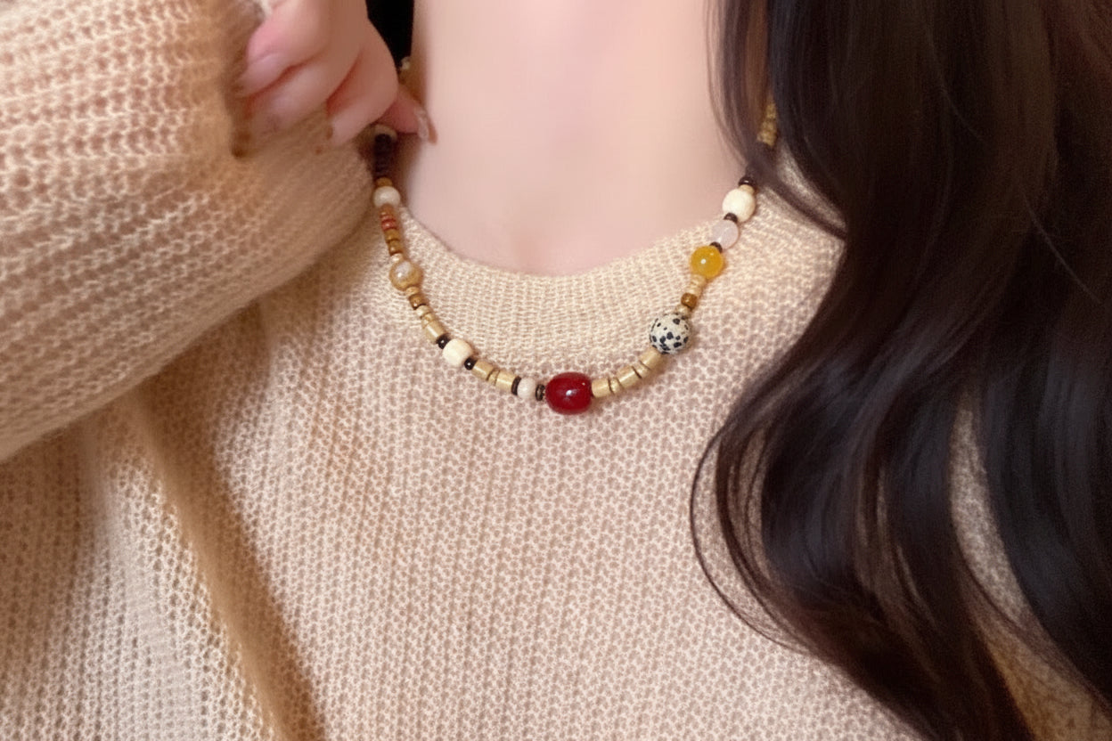 Close-up of a person wearing a beaded necklace with a neutral background