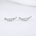 Close-up of a person wearing diamond stud earrings with one hand holding another earring.