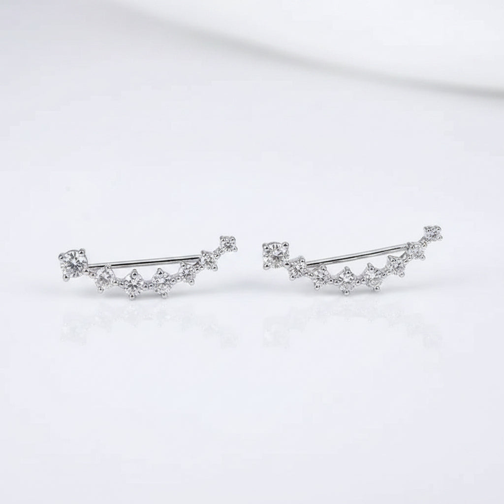 Close-up of a person wearing diamond stud earrings with one hand holding another earring.