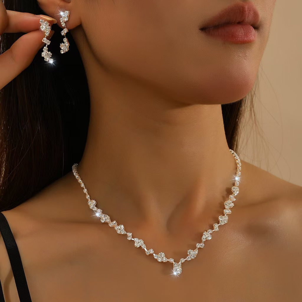 Close-up of a woman wearing a diamond necklace and earrings against a neutral background