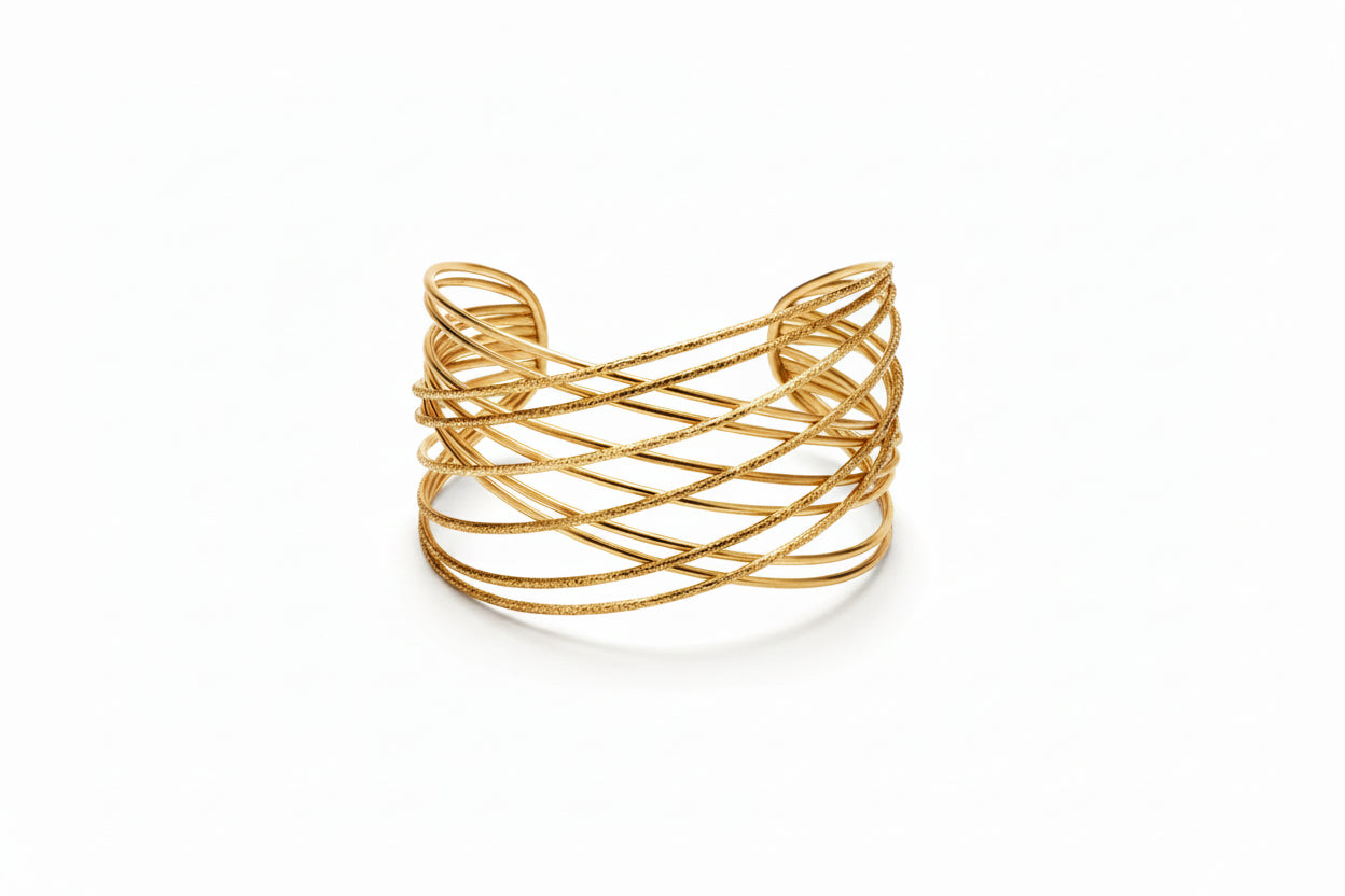 Close-up of a wrist wearing multiple golden bracelets with a neutral background