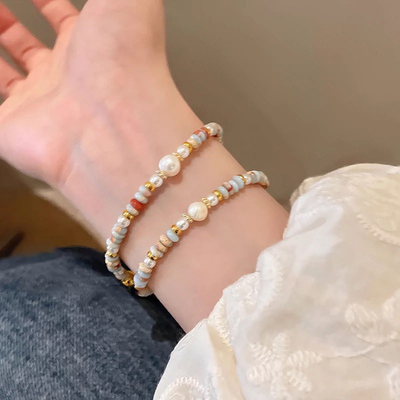 Close-up of a wrist wearing two pearl beaded bracelets on a neutral background