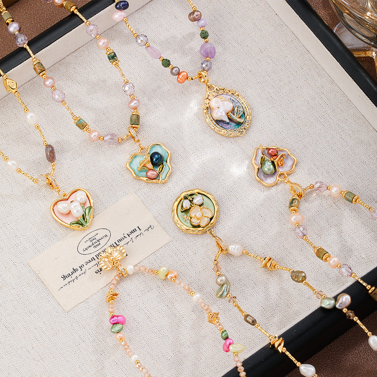 Delicate jewelry set with colorful beads and floral pendants on a textured surface.