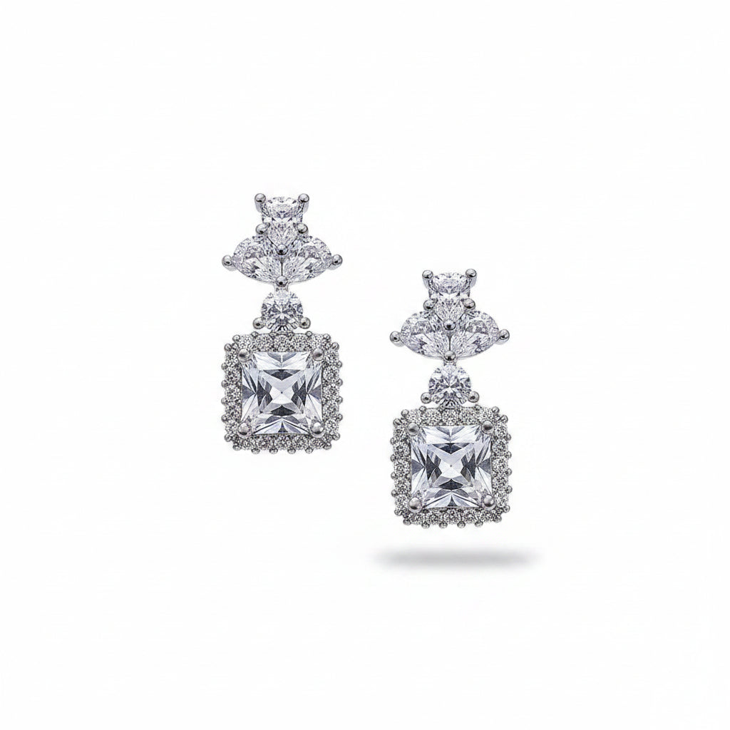 Diamond earrings held between fingers on a white background