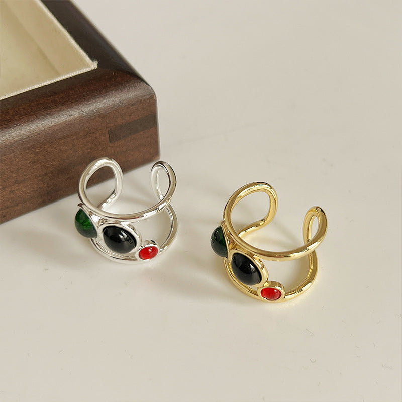 Gold and silver open-style earrings with colored stones on a light surface.