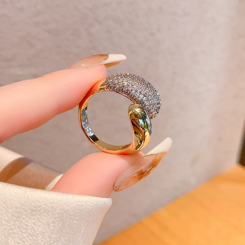 Gold and silver ring held between fingers against a neutral background