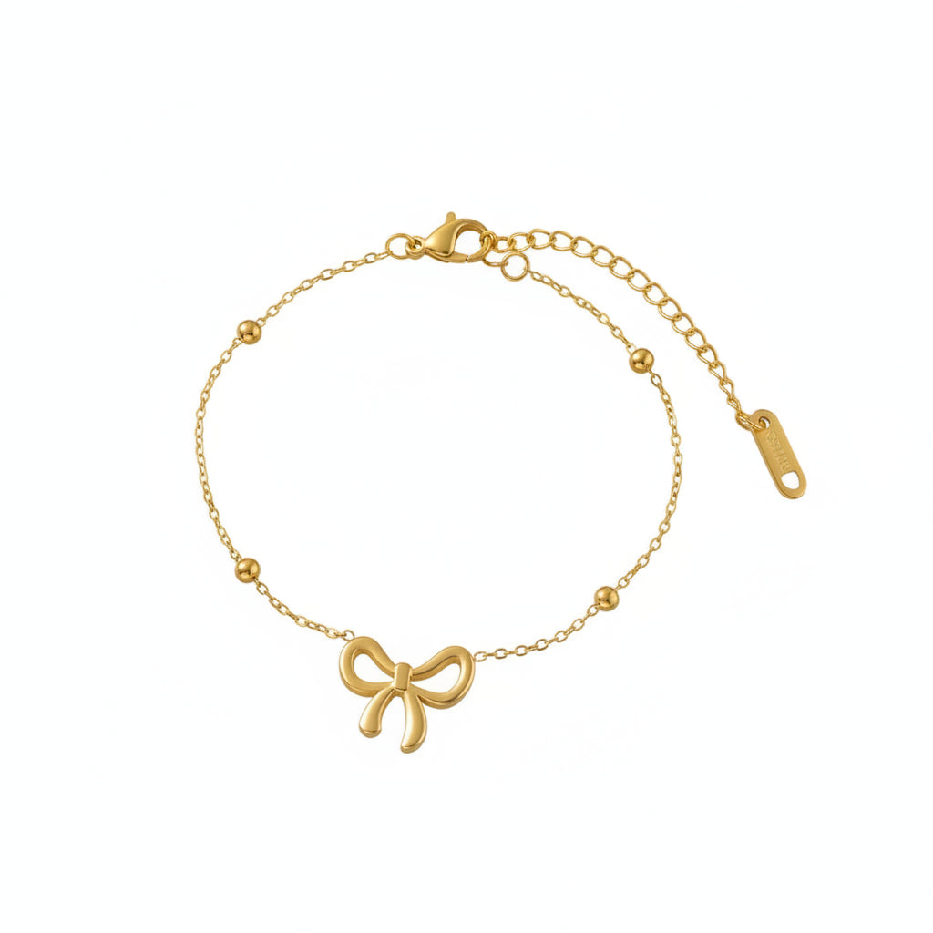 Gold bracelet with bow charm on a pink jewelry box