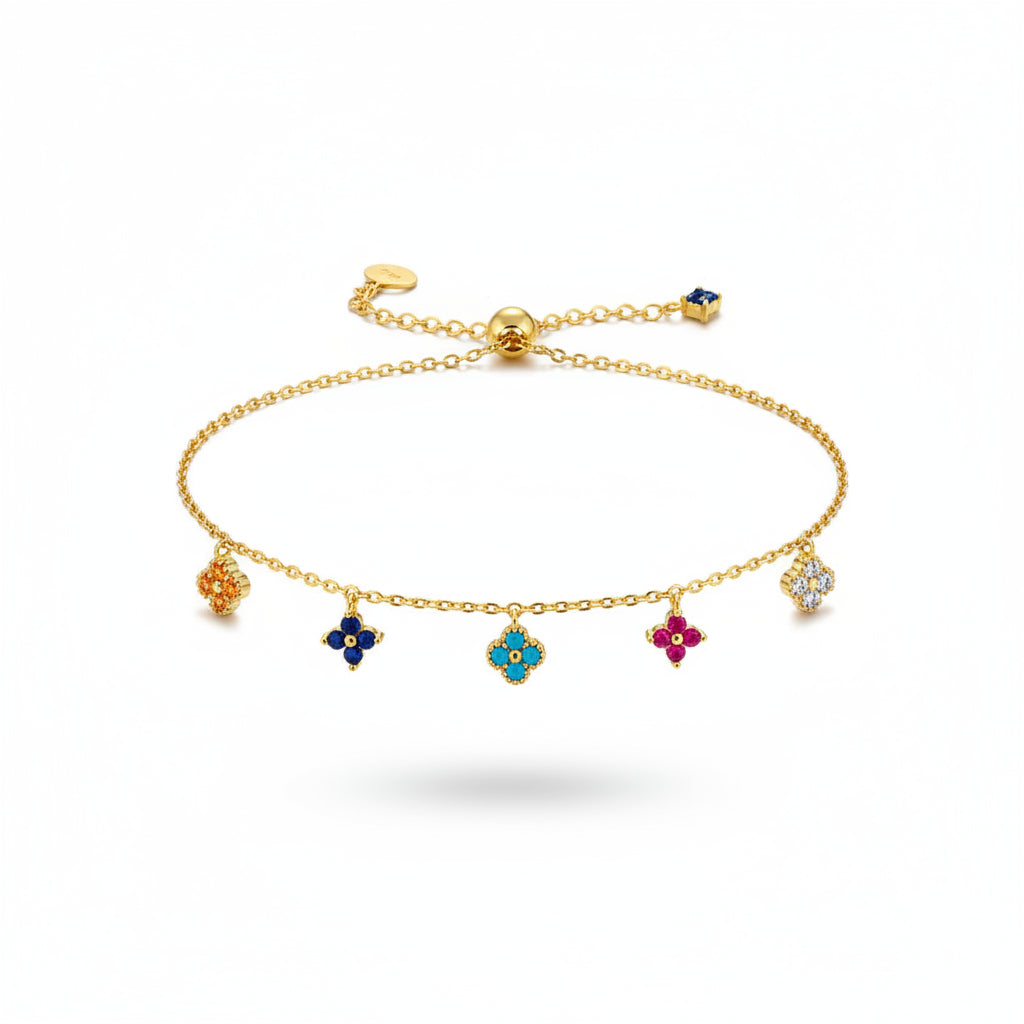 Gold bracelet with colorful charms on a hand against a neutral background