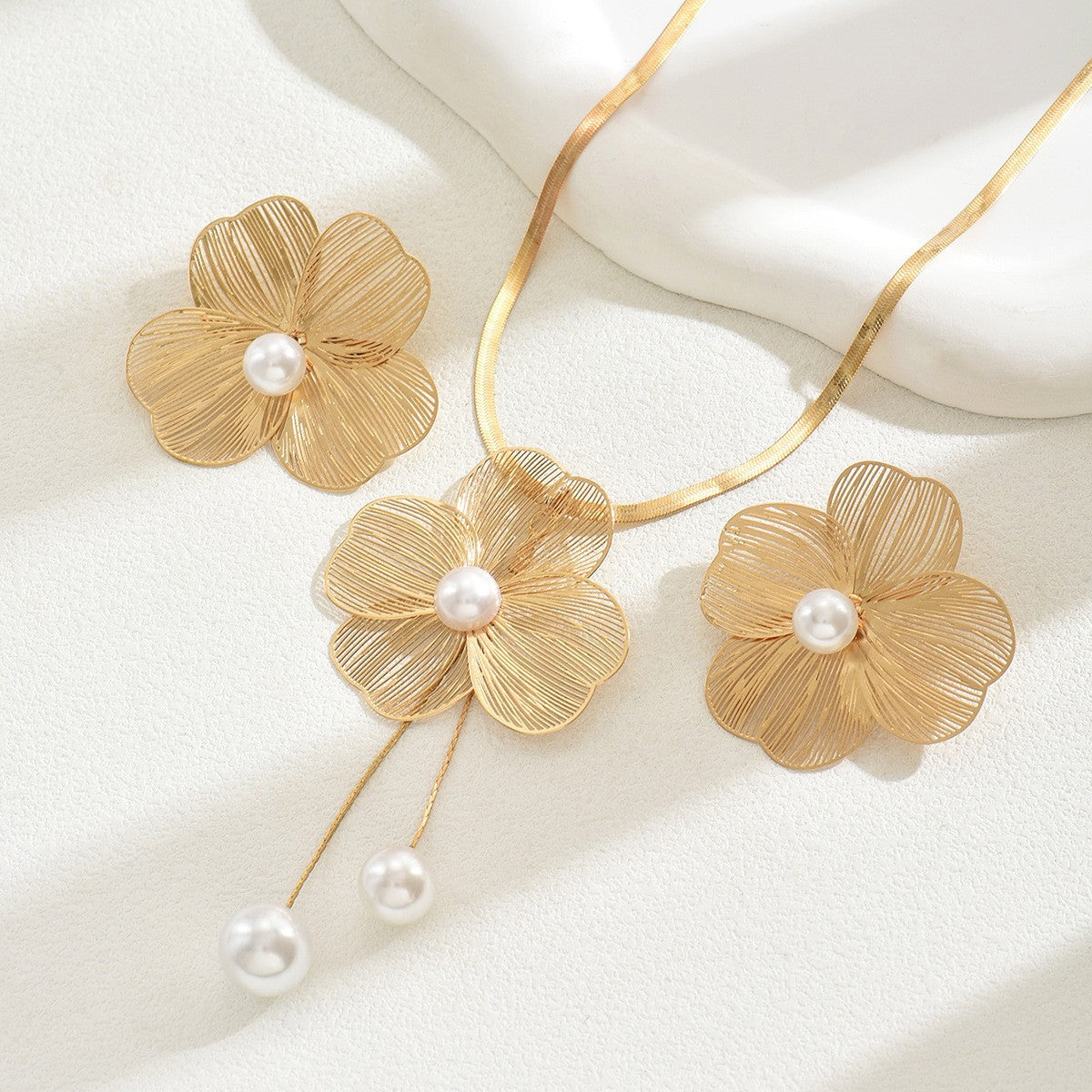 Gold floral necklace with pearls on a white background