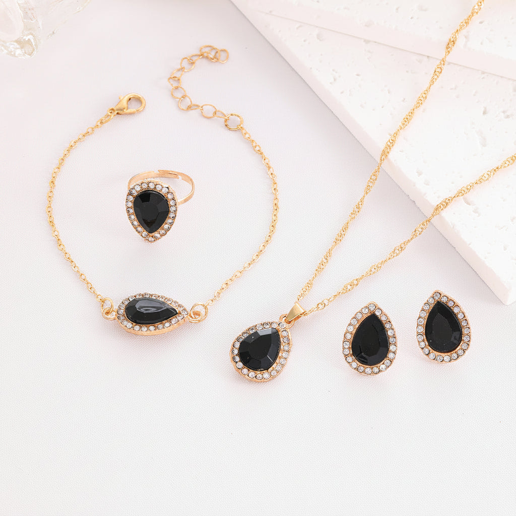 Gold jewelry set with black stones on a white surface