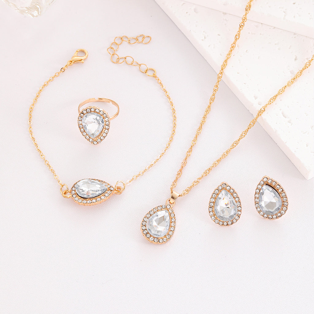 Gold jewelry set with teardrop-shaped crystals on a light background