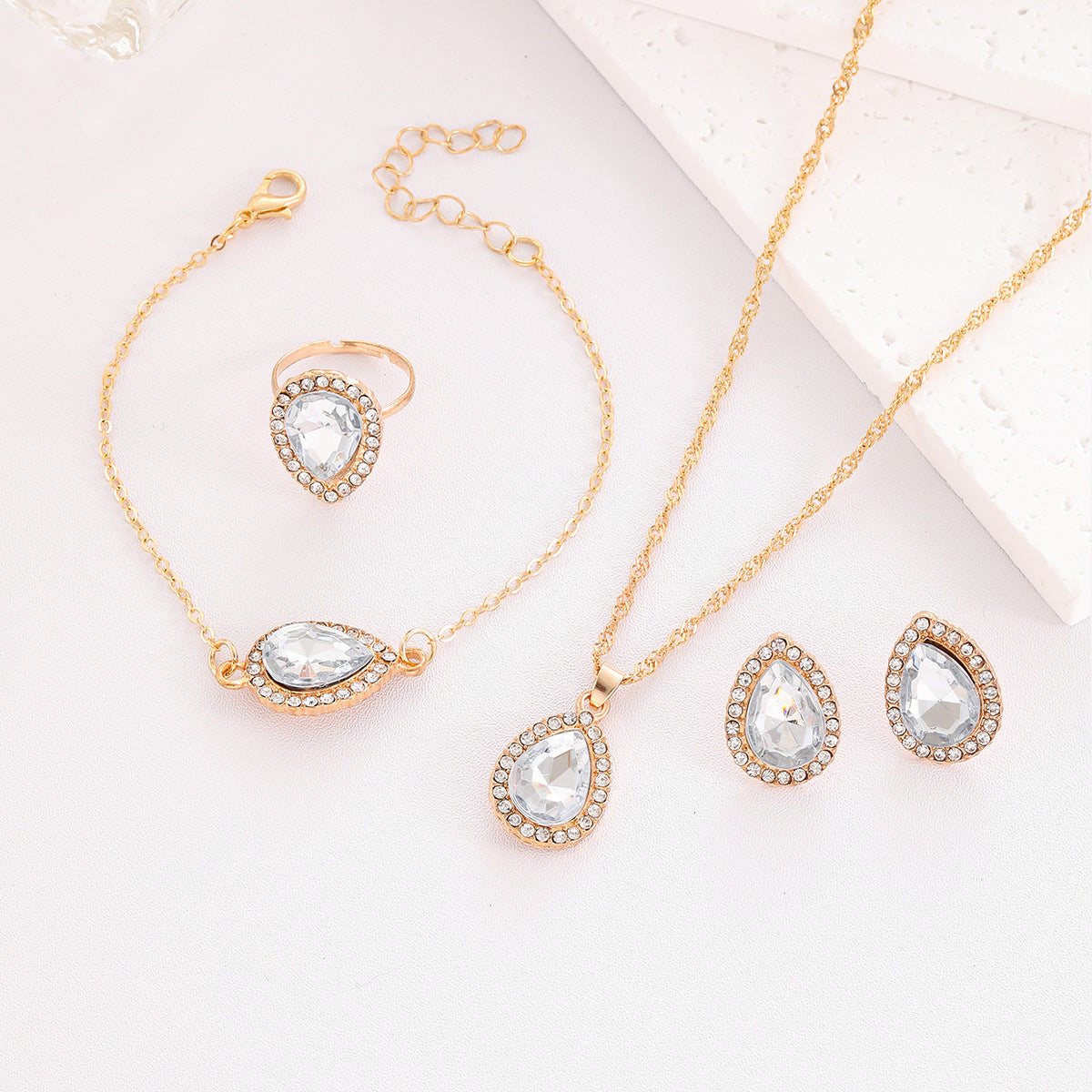 Gold jewelry set with teardrop-shaped crystals on a light background