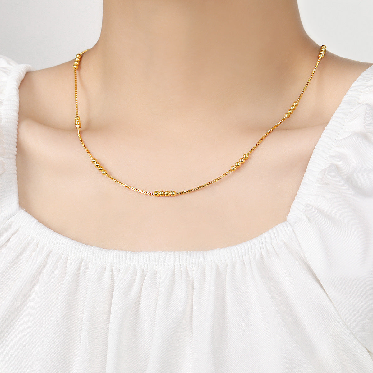 Gold necklace on a mannequin with a white background