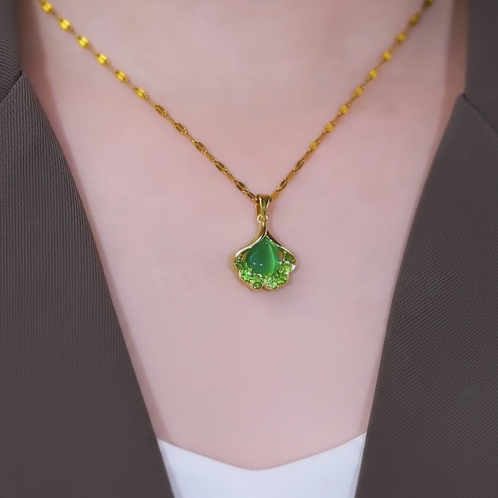 Gold necklace with a green pendant worn by a person