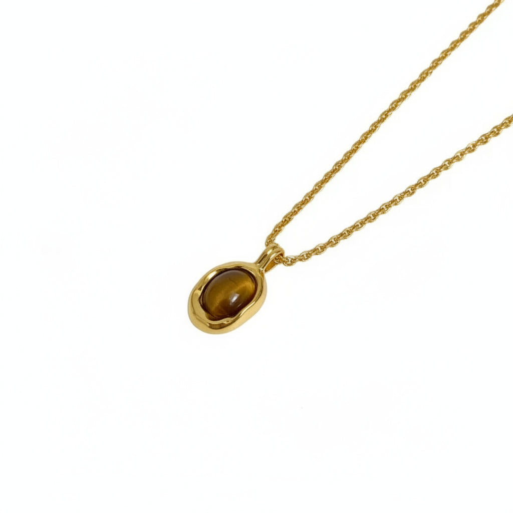 Gold necklace with a pendant on a wooden stand with a quote card.