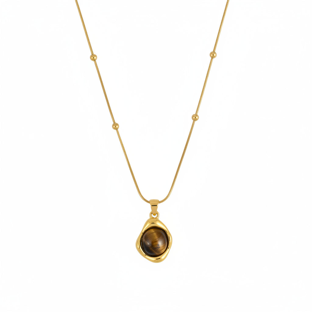Gold necklace with a pendant on a wooden tray with a card underneath