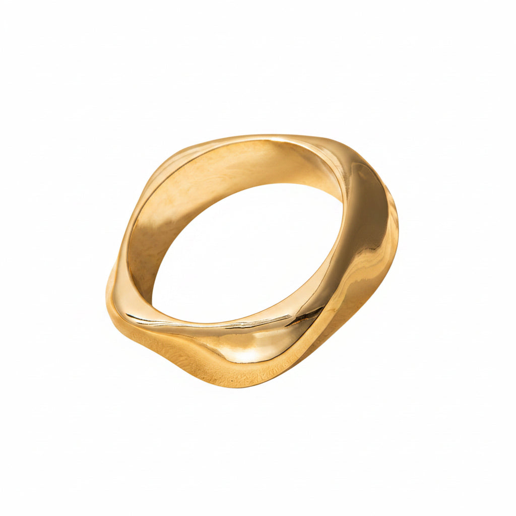Gold ring on a beige surface with a soft shadow