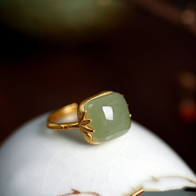 Gold ring with a green gemstone on a white surface
