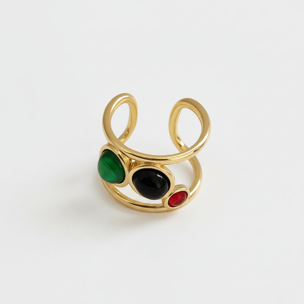 Gold ring with colored stones on a beige plate