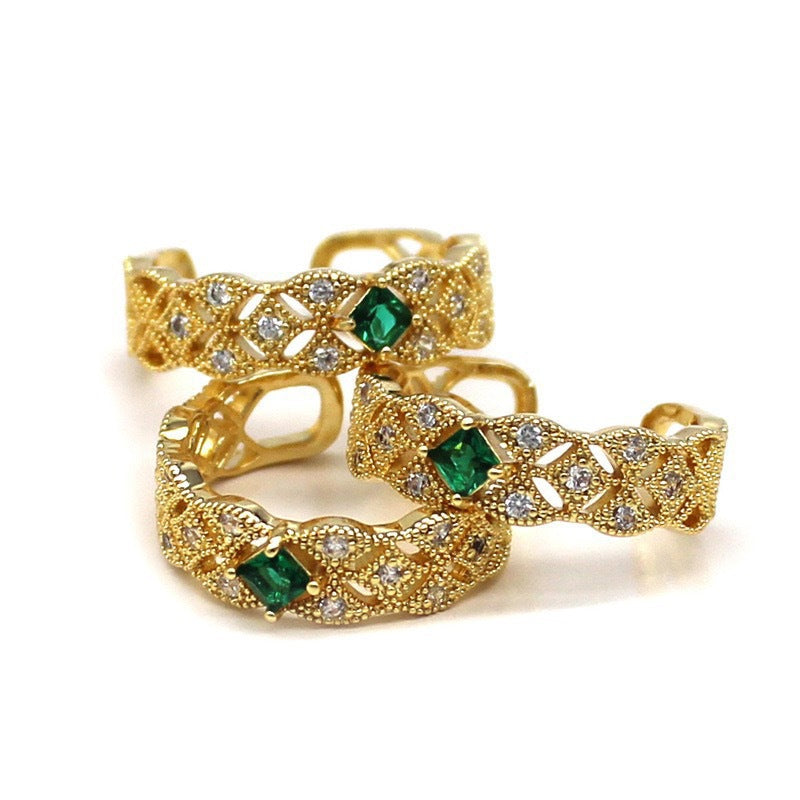 Gold rings with emerald and diamond accents on a white background