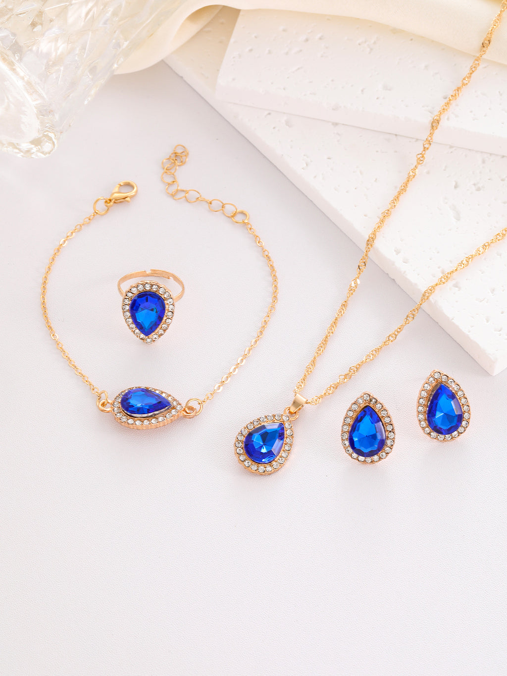 Jewelry set with blue teardrop stones on a white surface