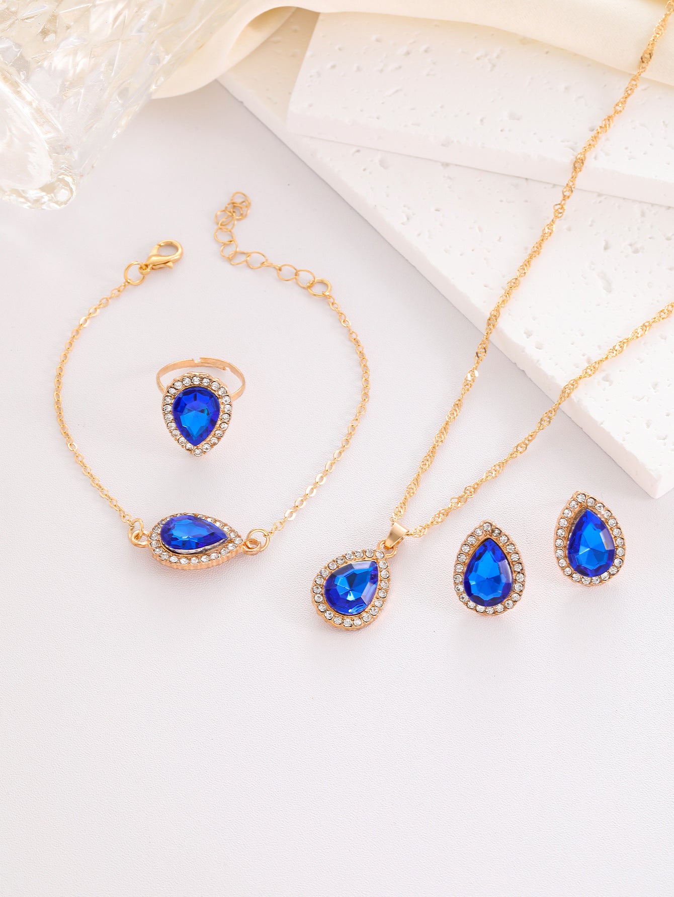 Jewelry set with blue teardrop stones on a white surface