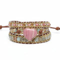Multistrand bracelet with pink heart charm on a wooden surface