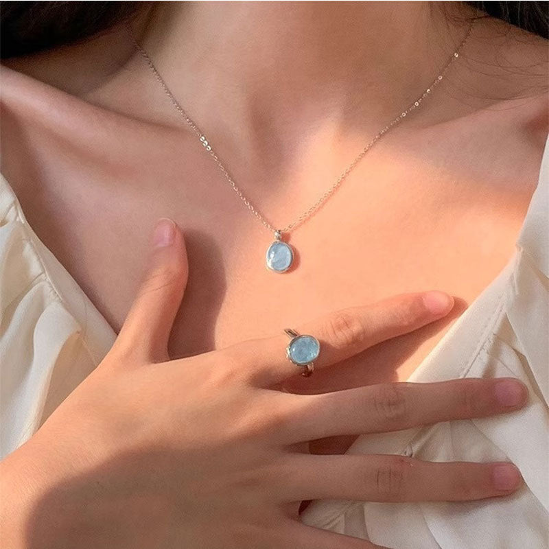 Necklace and ring with a blue gemstone worn by a person