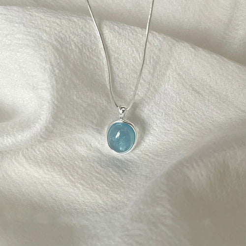 Necklace with a blue pendant on a white fabric background