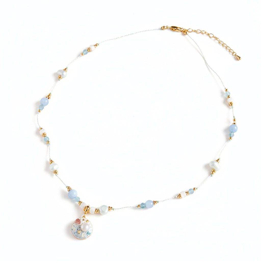 Necklace with beads and a decorative pendant on a light background
