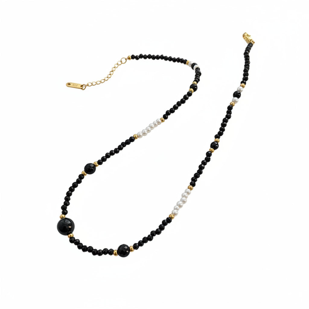 Necklace with black and gold beads on a wooden stand with a card underneath