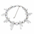 Necklace with clear crystal-like pendants on a reflective surface