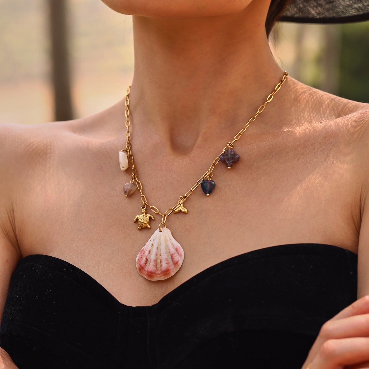 Necklace with shell pendant and turtle charm worn by a person