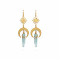 Gold earrings with sun and moon designs on a stone surface