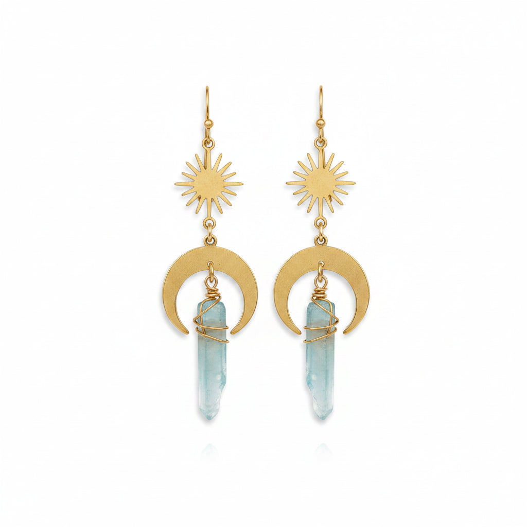 Gold earrings with sun and moon designs on a stone surface
