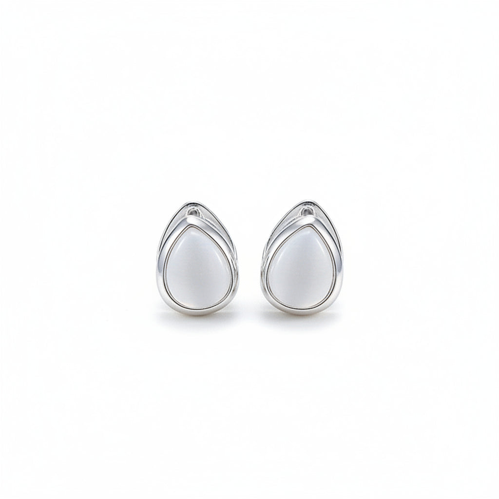 Pair of silver earrings with white stones on a light beige background