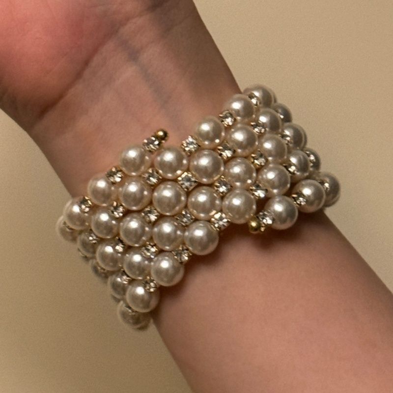 Pearl bracelet on a wrist against a neutral background