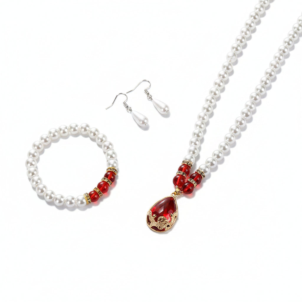 Pearl jewelry set with red accents on a beige surface