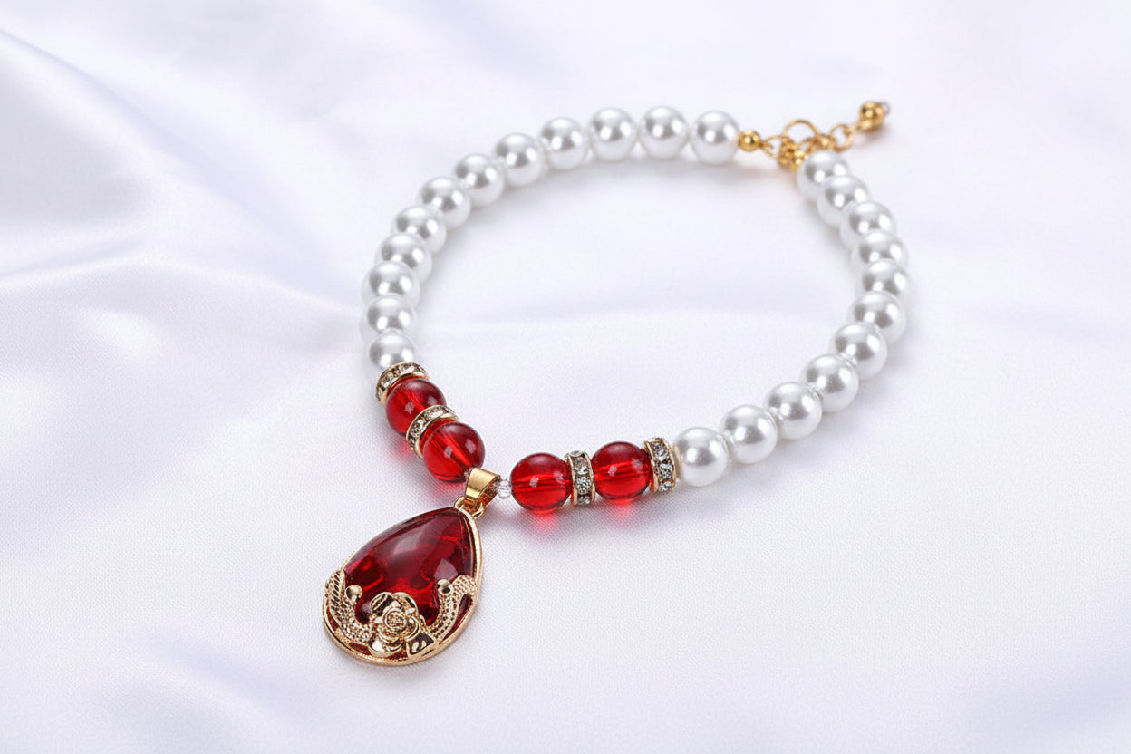 Pearl necklace with a red and gold pendant in a red jewelry box on a white background