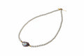Pearl necklace with a unique pendant on a textured surface