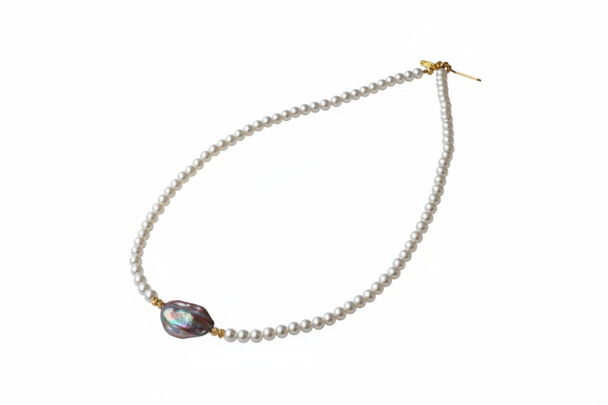 Pearl necklace with a unique pendant on a textured surface