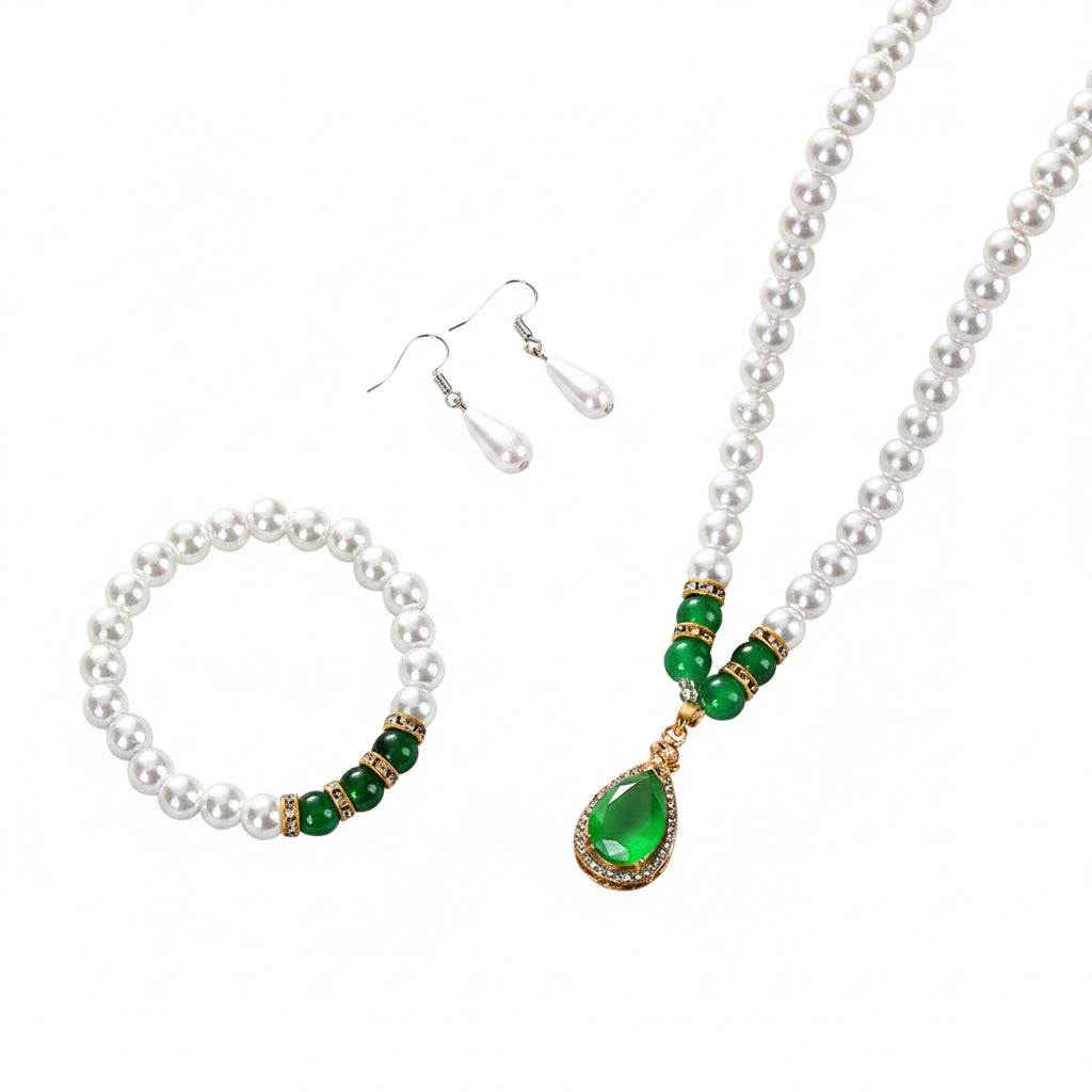 Pearl necklace with green beads and a teardrop pendant, pearl bracelet, and matching earrings on a beige surface.