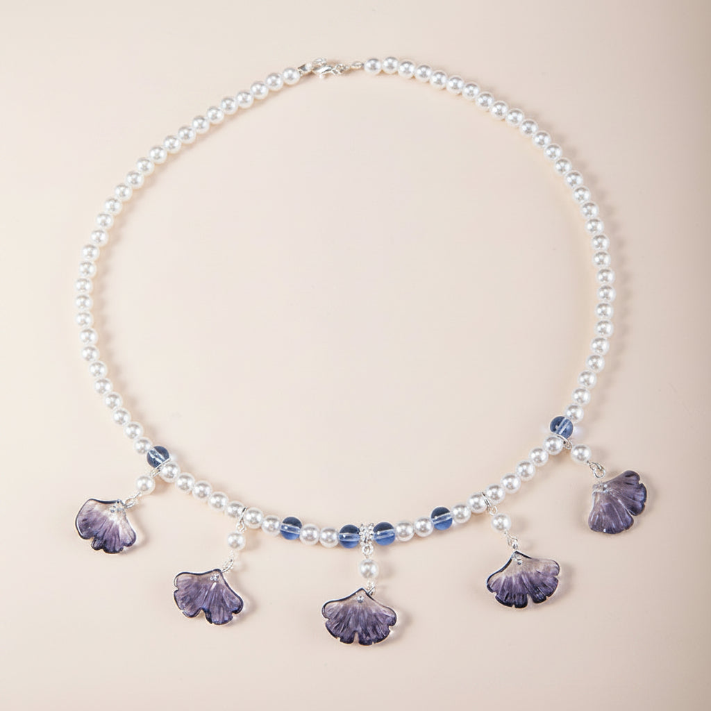 Pearl necklace with purple shell-like pendants on a beige background