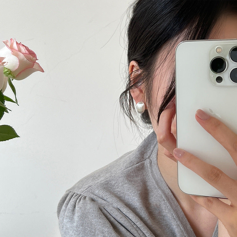 Person holding a smartphone with a white background and a pink rose on the side.